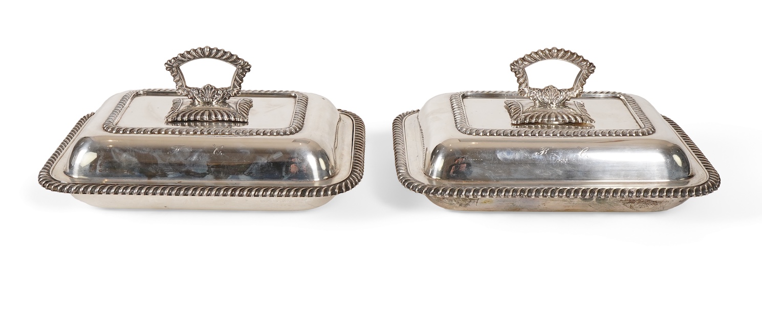 A matched pair of George V silver rectangular entrée dishes and covers, both with gadrooned borders and similar unmarked handles, Ellis & Co, Birmingham, 1923 and Ellis & Co, Birmingham, 1932, base 27.8cm, 108.3oz, exclu